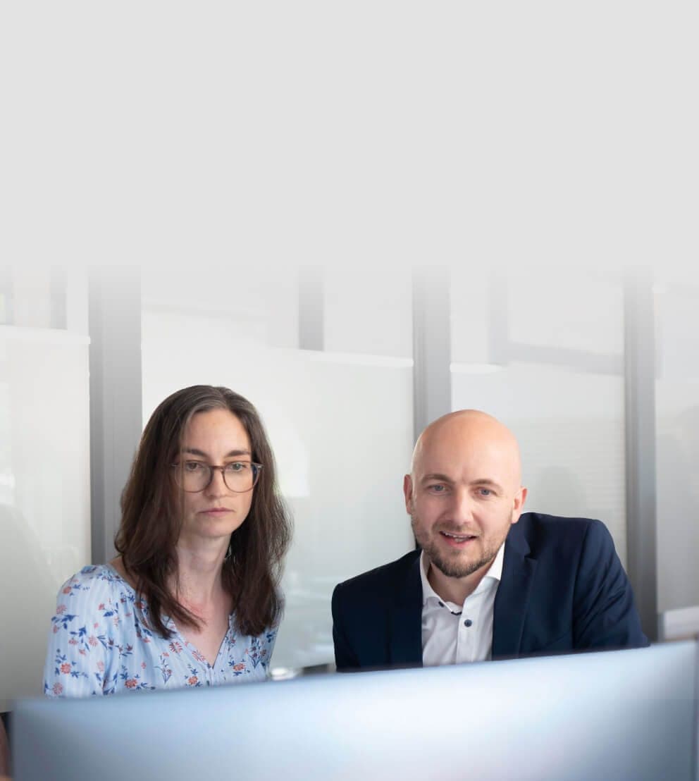 Beraterin und Berater prüfen konzentriert Inhalte auf einem Monitor